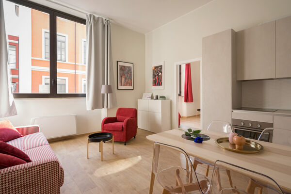 Lichte woonkamer van een modern ingericht appartement met eettafel en rode fauteuil