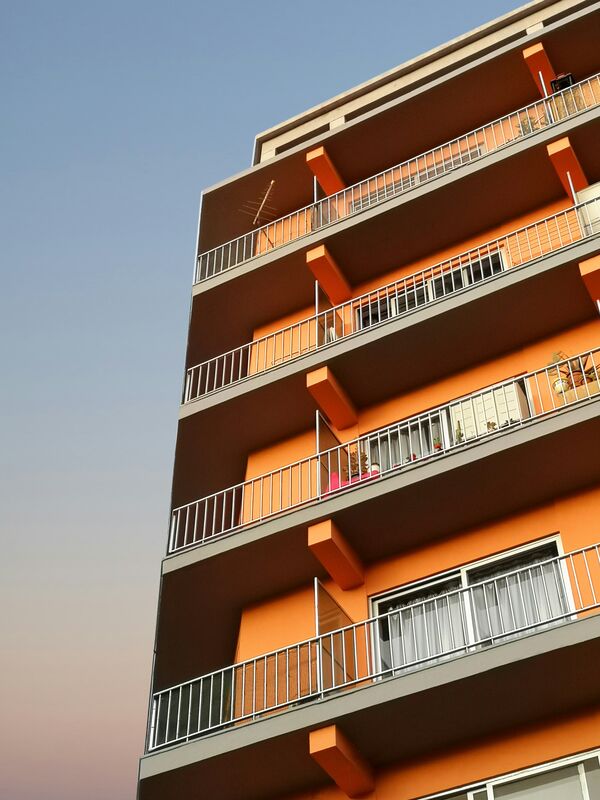 Oranje appartementsgebouw met balkons tegen een blauwe lucht