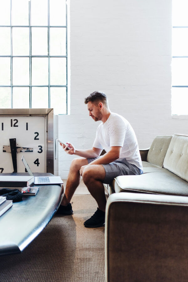 Man bekijkt zijn smartphone op de zetel in een ruime loft