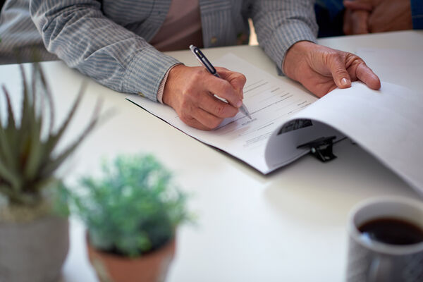 Persoon ondertekent een verkoopdocument aan tafel